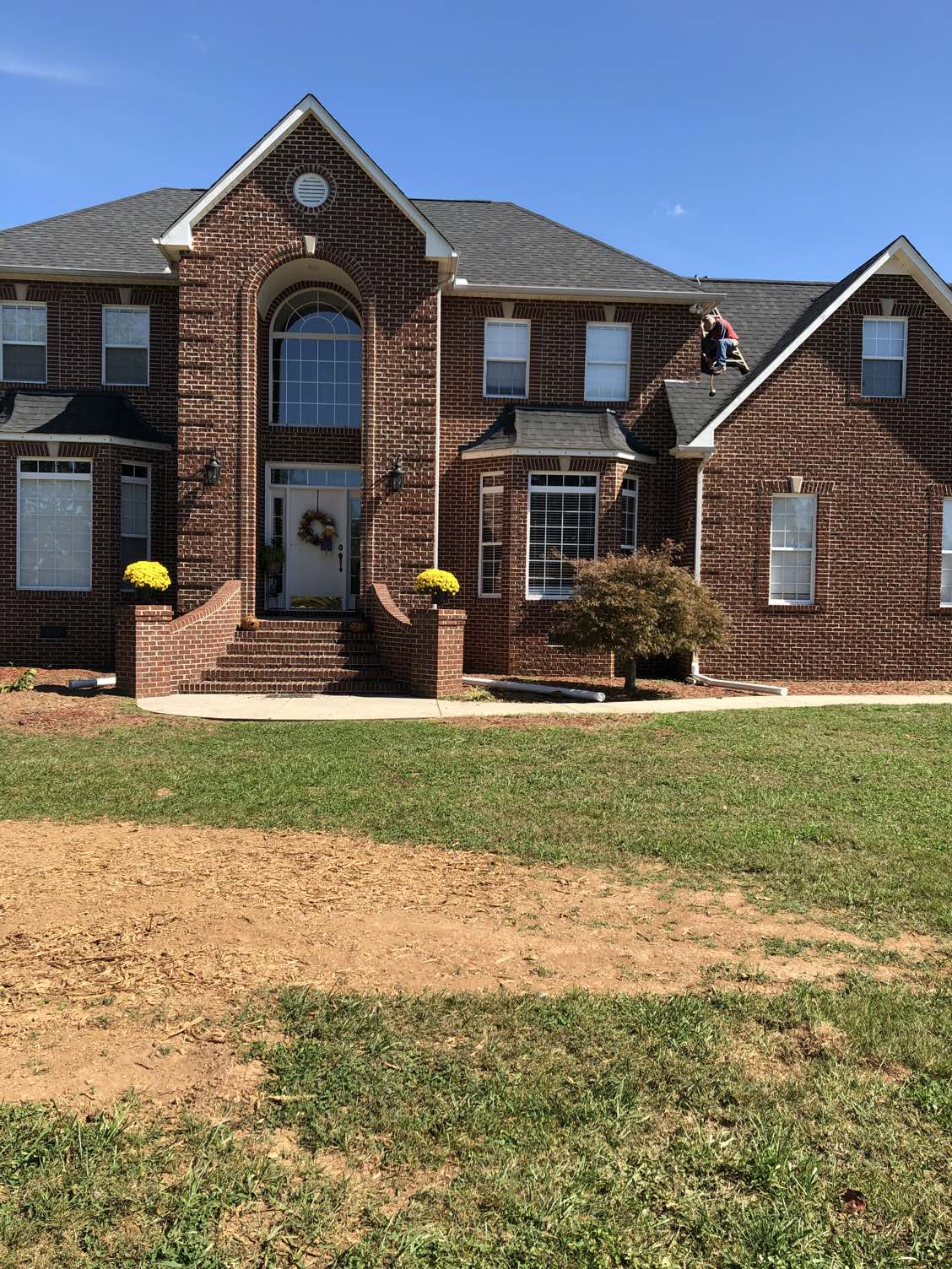 Large brick home with roof work in progress